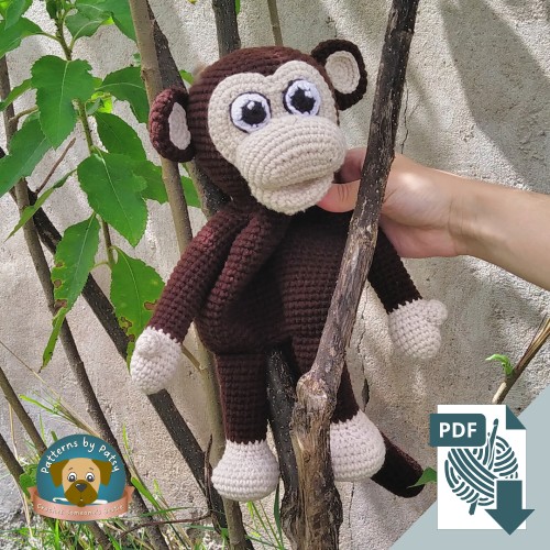 Charlie the low-sew crochet monkey lovey held outdoors in a small tree.