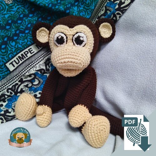 Brown and cream crochet monkey lovey with long arms and legs, sitting on a blanket, designed by Patterns by Patsy.