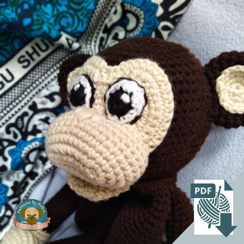 Close up of Charlie the crochet monkey lovey face showing crocheted eyes and textured amigurumi stitches.