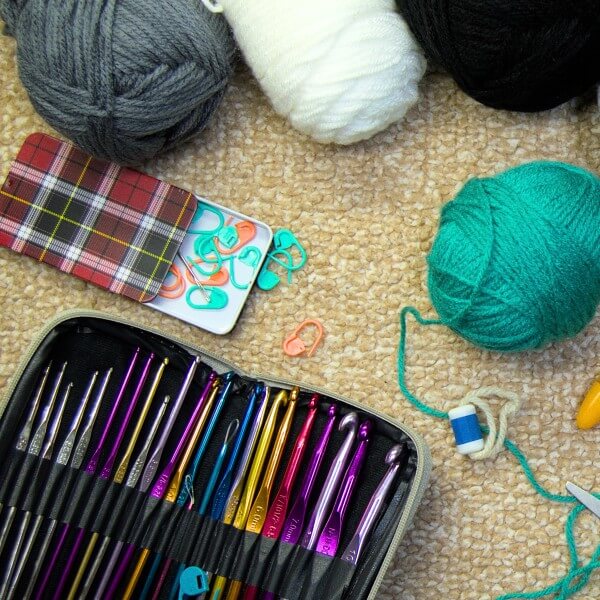 Crochet workspace with yarn, stitch markers, and crochet hooks arranged neatly on a table.
