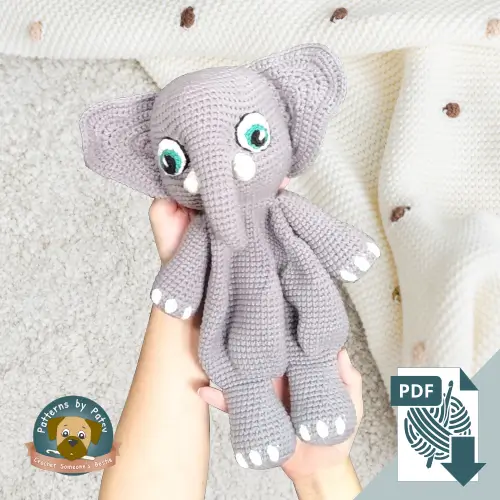 The finish item from my crochet elephant lovey pattern being held over a baby blanket, showcasing the finished result of a digital crochet elephant lovey pattern.