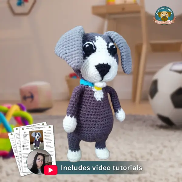 Free Puppy Crochet Pattern with Step-by-Step Video Tutorials Crochet Puppy Dog amigurumi standing upright in a child’s room, with a small inset showing the pattern pages and YouTube icon labeled ‘Includes video tutorials.